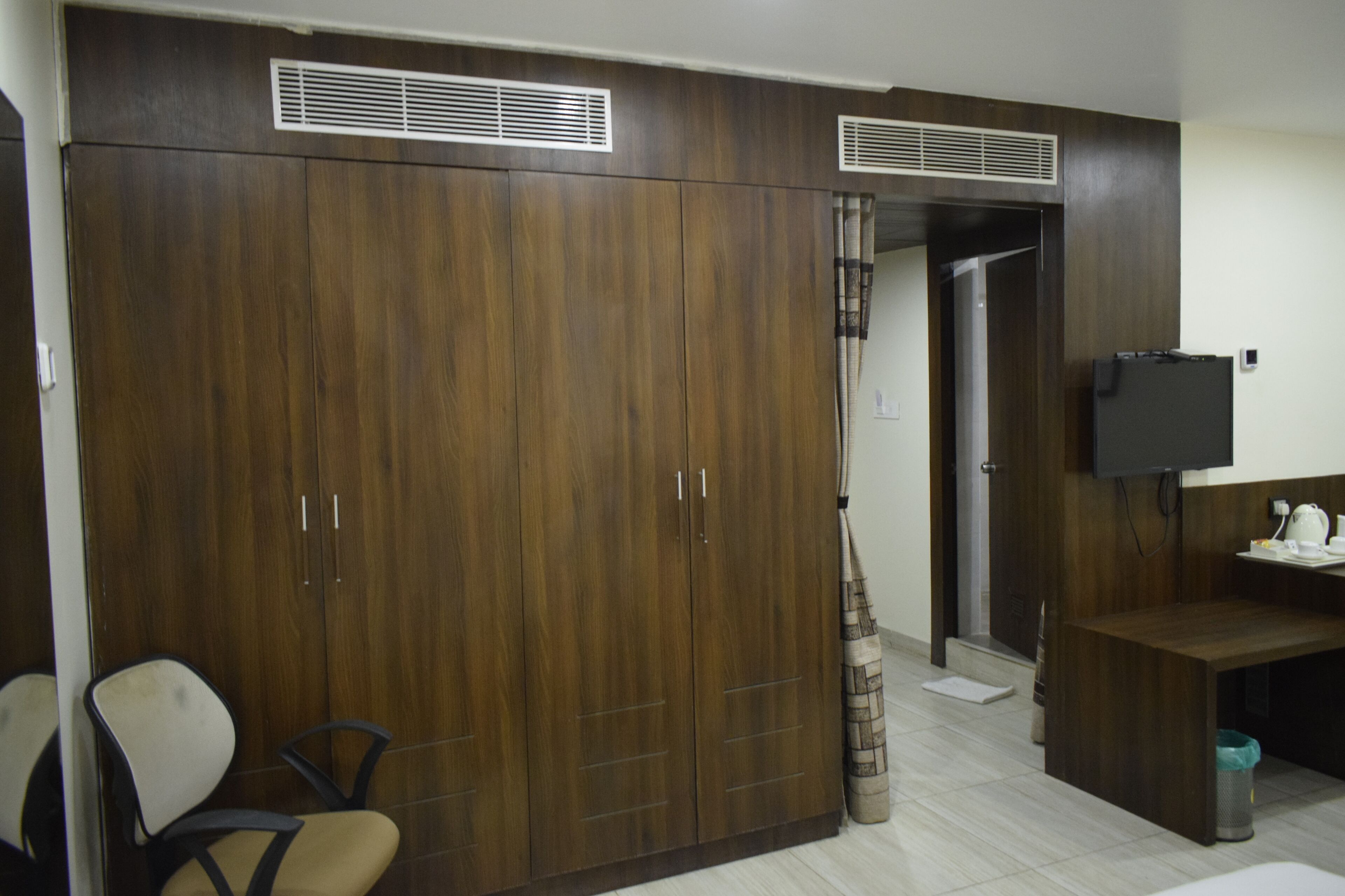 Ein Zimmer mit Kleiderschrank, Schreibtisch, Stuhl und Fernseher.