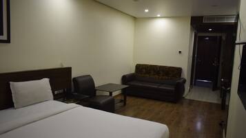 Una habitación de hotel con una cama grande, un sofá, una mesita y un escritorio.