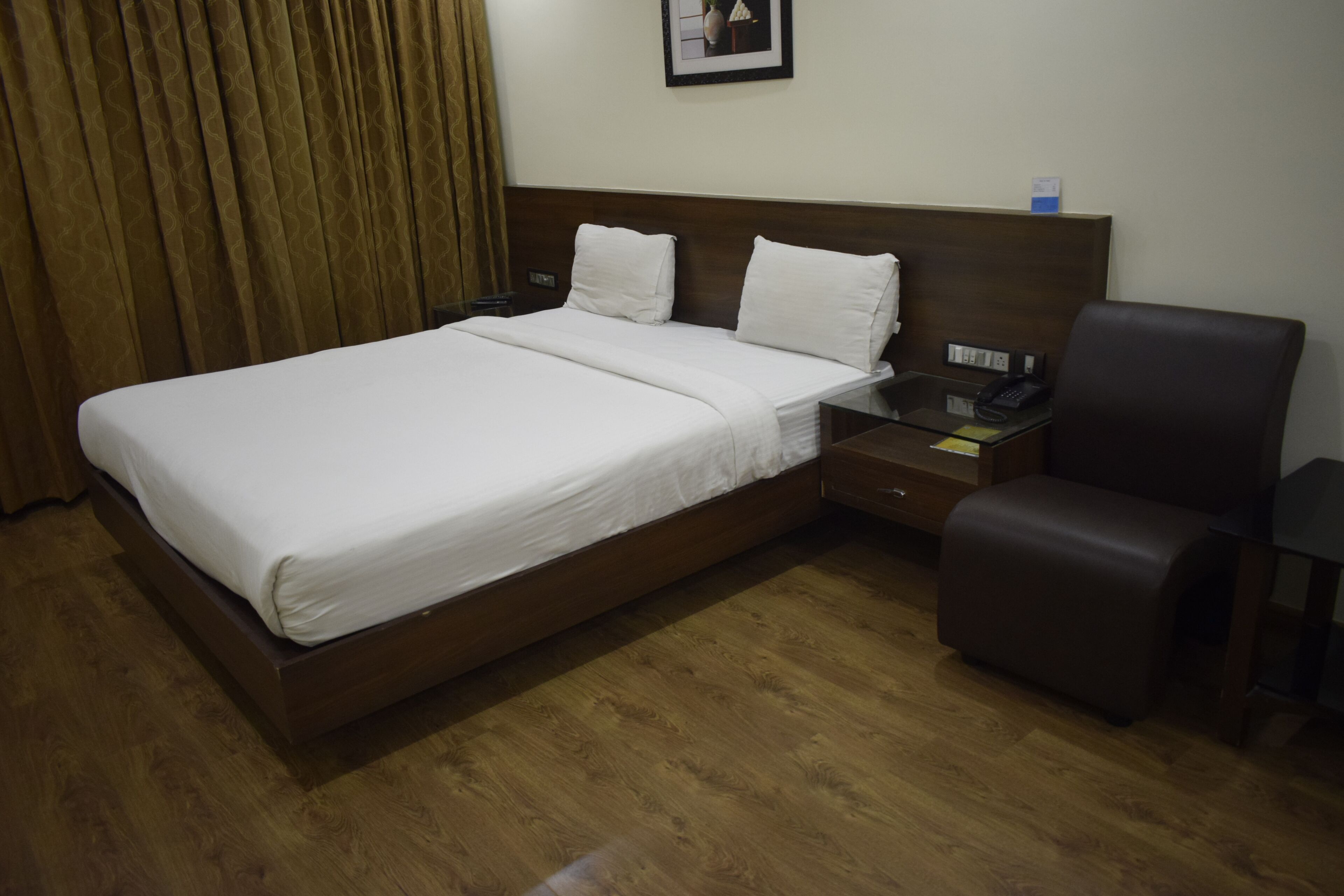 A hotel room with a large bed, a bedside table with a phone, and a chair.