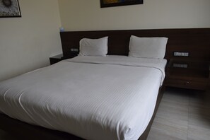 A neatly made bed with white linens in a hotel room. - Grand Kubera (Viluppuram)