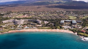 An aerial view of a coastal resort with multiple hotel buildings, a beach, and surrounding hills. - I.P.M PRESENTS: HOOLEI 93-1: 3 BEDROOMS + OFFICE. FLEXIBLE CANCELATION POLICY (Kihei)