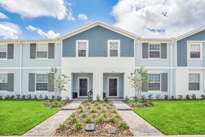 A two-story residential building with a symmetrical facade, a central entrance, and a well-maintained lawn with a stone pathway leading to the entrance. - Toy Story & Disney Rooms • Private Pool • Lazy River • Near Disney (Davenport)