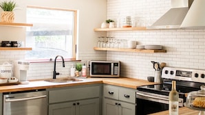 A modern kitchen with white brick backsplash, stainless steel appliances, and wooden countertops. - The Cozy Cabernet - short walk to Main St! (Fredericksburg)