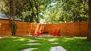 A backyard with a wooden fence, red chairs, and a fire pit. - The Cozy Cabernet - short walk to Main St! (Fredericksburg)