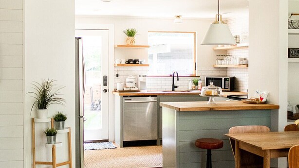A modern kitchen with a central island, wooden dining table, and a bright red sofa. - The Cozy Cabernet - short walk to Main St! (Fredericksburg)
