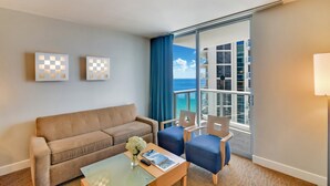 A hotel room with a balcony, a sofa, two armchairs, a coffee table, and artwork on the wall. - Marenas Ocean View Apartment (Sunny Isles Beach)