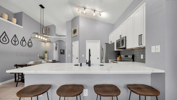 Une cuisine moderne dotée d’un grand îlot central, de tabourets de bar et d’un luminaire suspendu.