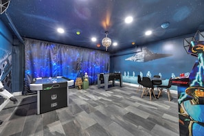 A room with a starry ceiling, a large space-themed mural, a foosball table, and a Star Wars-themed table. - Disney Themes Villa, Pool+Gameroom, Near Parks, Sleeps 8 (Kissimmee)