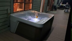 Un bain à remous situé dans un espace extérieur abrité, doté d’une terrasse en bois et d’une fenêtre donnant sur les environs.