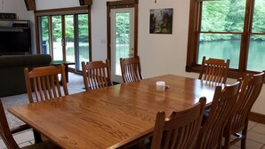 Un coin repas avec une table et des chaises en bois, un téléviseur et un tableau accroché au mur.