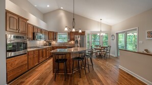 A spacious kitchen with wooden cabinets, stainless steel appliances, and a large island with bar stools.