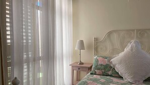A bedroom with a bed, a nightstand, a lamp, and sheer curtains. - 2 Bed Penthouse - Sleeps 4 - Pool - Sea Views (Finestrat)
