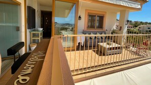 A balcony with a view of the city, a sofa, and a table with a sign. - 2 Bed Penthouse - Sleeps 4 - Pool - Sea Views (Finestrat)