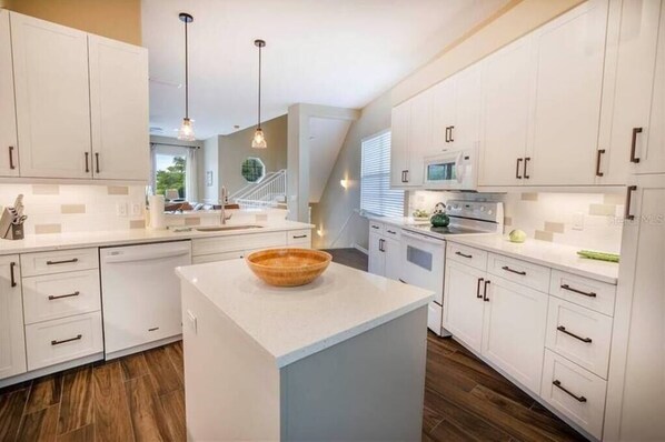 Enjoy cooking in this well-lit kitchen with a central island, white cabinetry, and stainless steel range hood.