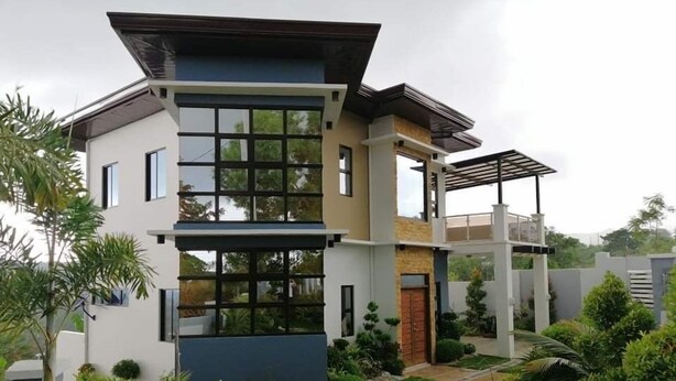 Uma casa moderna de dois andares com telhado plano, janelas amplas e um jardim bem cuidado.