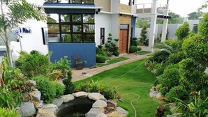 Uma casa moderna com um jardim bem cuidado, incluindo um lago e diversas plantas.