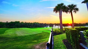 A golf course with a clear view of the sunset, palm trees, and a fenced area. - LUXURY Modern Reunion Resort Home . Golf Course Views, Pool Access, near Disney! (Kissimmee)