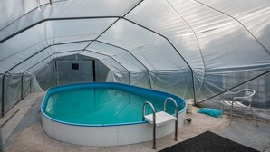 Ein kuppelförmiges Zelt mit Swimmingpool, einer Leiter und einem Stuhl.