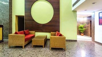 A lobby with wicker furniture, a circular wall decoration, and a potted plant.