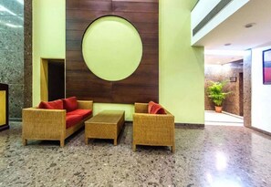 Un vestíbulo con muebles de mimbre, un adorno circular en la pared y una planta en maceta.