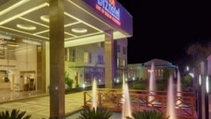 L’entrée d’un hôtel, avec un panneau indicateur, un espace abrité et un élément décoratif aquatique.