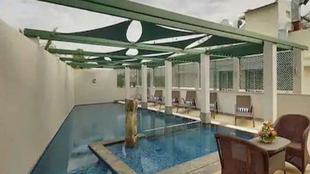 Une piscine dotée d’une structure en verre, de chaises longues et d’un espace salon abrité.