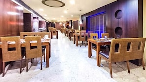 Une salle à manger d’hôtel avec de nombreuses tables et chaises, des murs en bois et un sol en marbre.