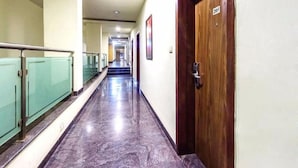 Un long couloir bien éclairé, doté d’un sol en marbre, de rampes en verre et de portes en bois.