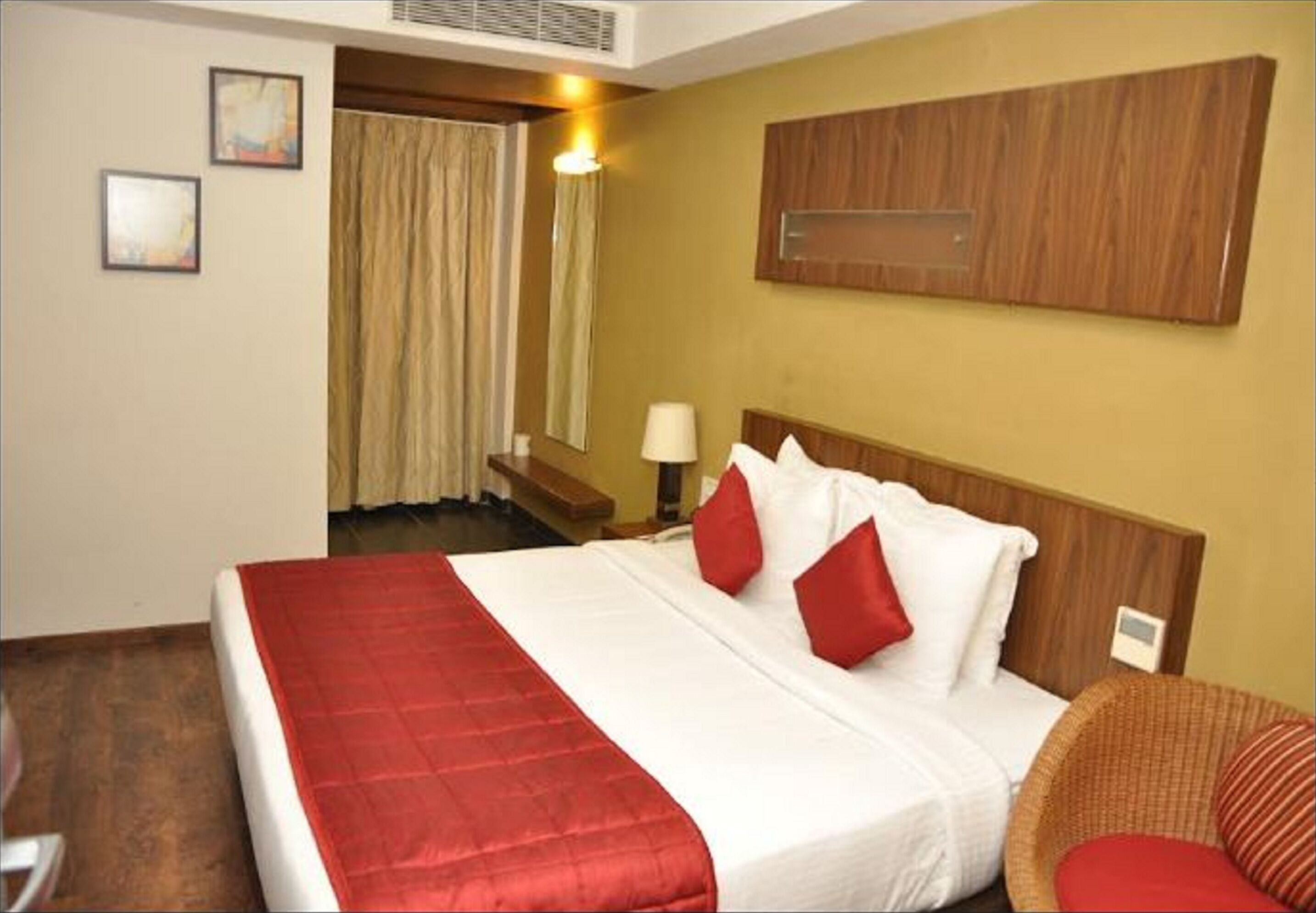 A hotel room with a bed, a chair, a desk, and a window with curtains.