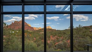 Una habitación con ventanas amplias que ofrecen vistas a formaciones rocosas rojas y vegetación verde.