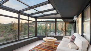 Una habitación moderna con un tragaluz grande, un sofá, una pequeña mesa redonda y una alfombra colorida.