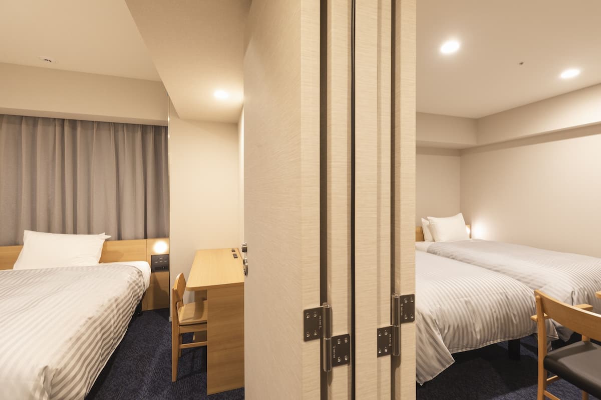 A hotel room with two beds, a desk, and a chair.