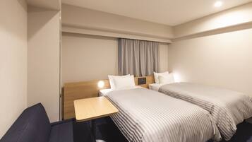 Habitación de hotel con dos camas, un escritorio y una silla.