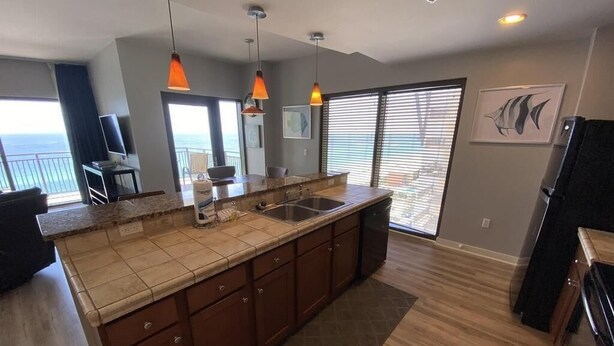 A modern kitchen with a large island, wooden cabinets, and a view to the outside. - Beautiful Beachfront luxury living at its best (Panama City Beach)