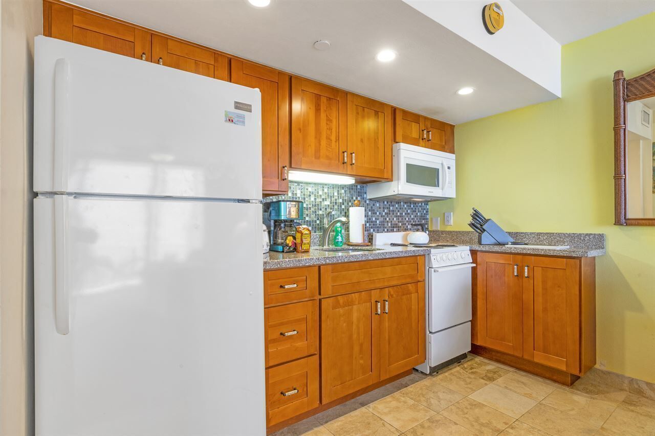 A kitchen with wooden cabinets, a white refrigerator, a microwave, and a stove.