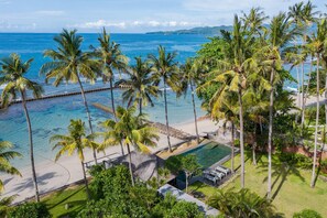 Um resort tropical com piscina, palmeiras e uma praia.