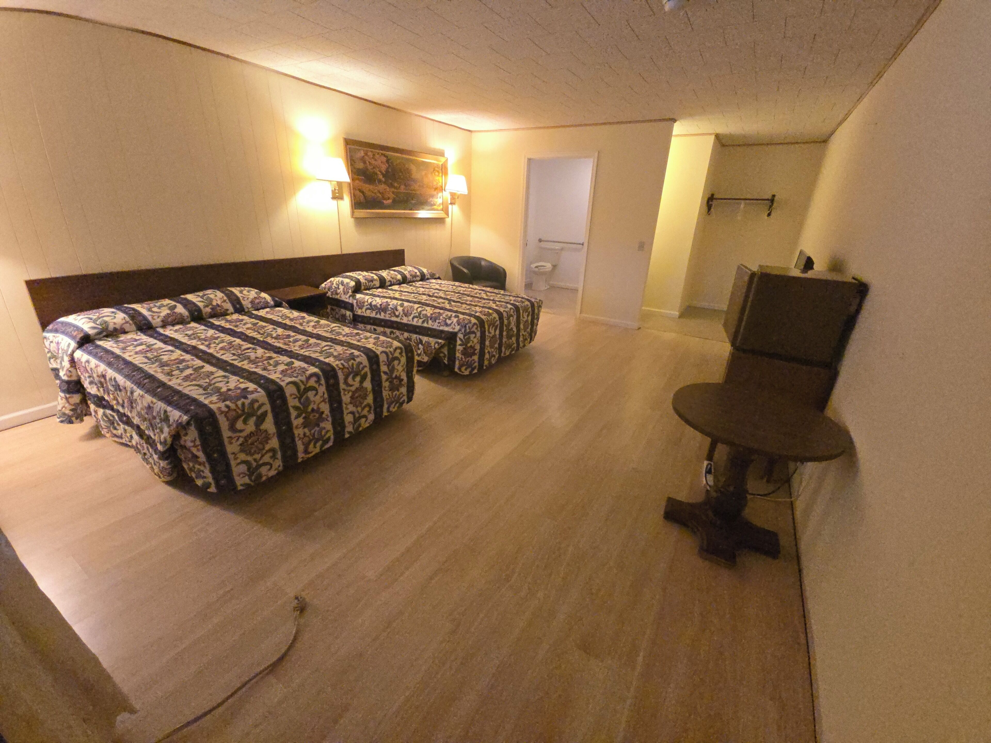 Een hotelkamer met drie bedden, een bureau en een stoel.