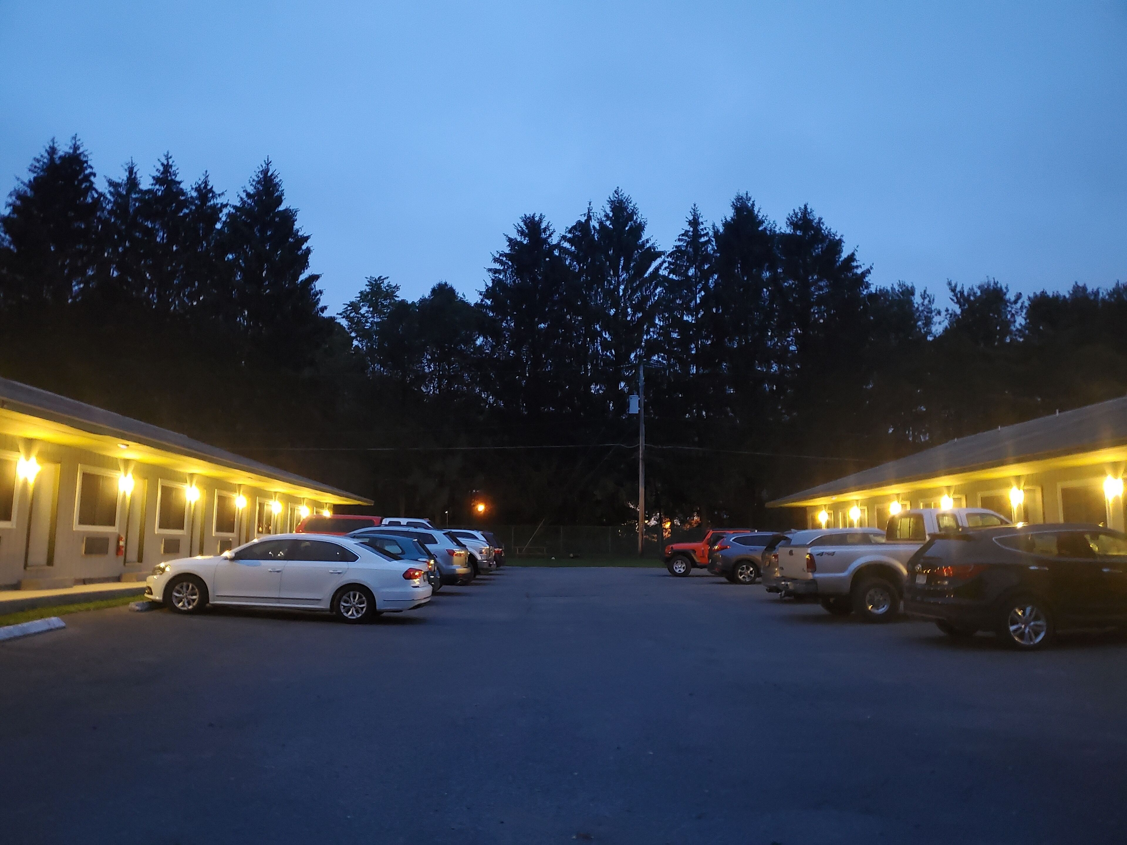 A parking lot with several cars parked in front of a row of motel buildings.