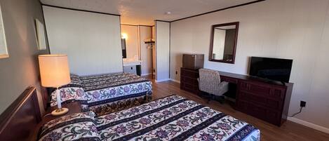 Habitación de hotel con dos camas, un escritorio, una silla, un televisor y un espejo.