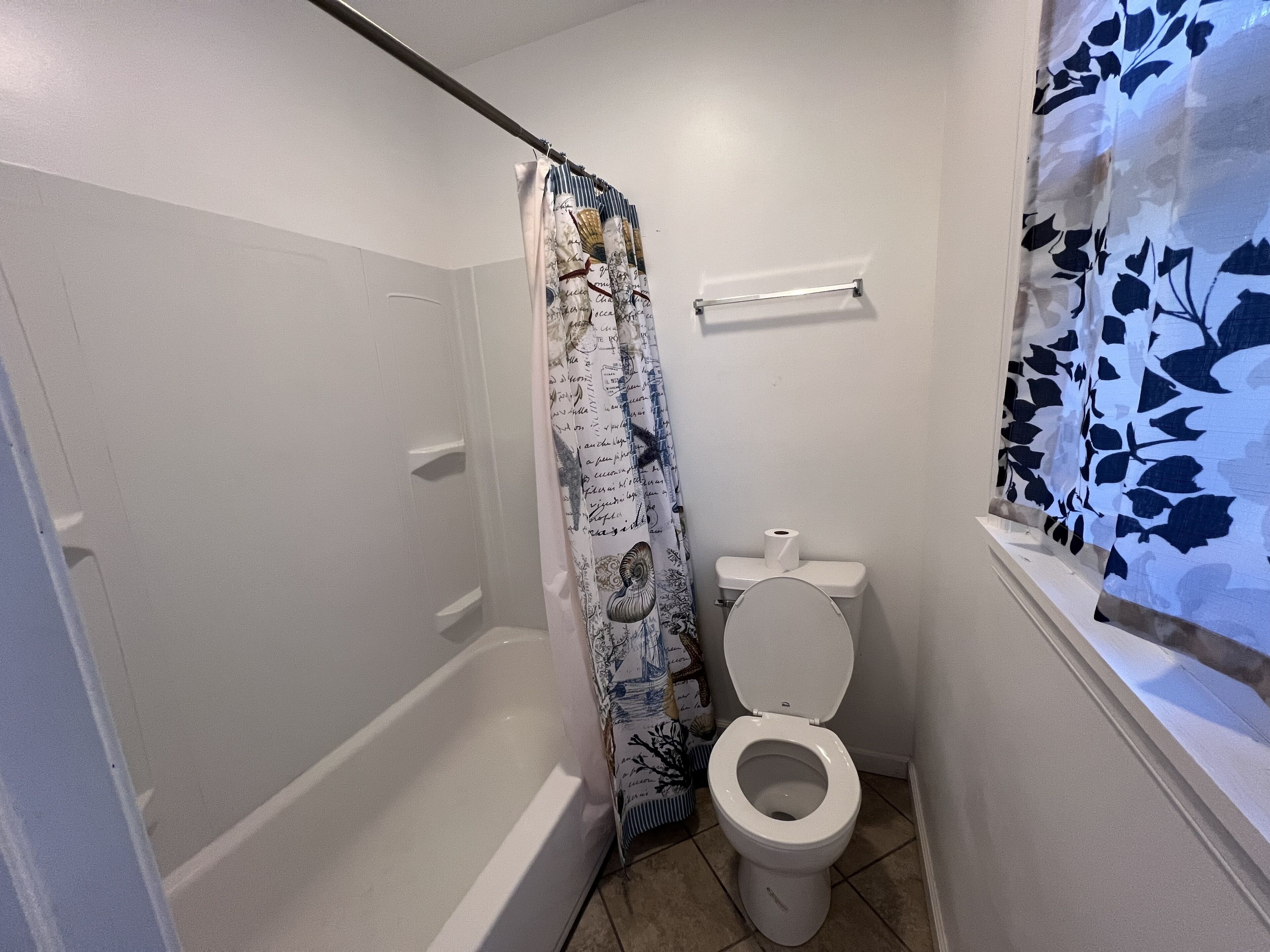 Un baño pequeño con bañera, inodoro y cortina de ducha.