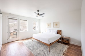 A bedroom with a bed, a ceiling fan, a nightstand, and a patterned rug.