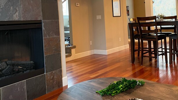 Un salon avec une cheminée, un coin repas avec une table et des chaises, et un téléviseur fixé au mur.