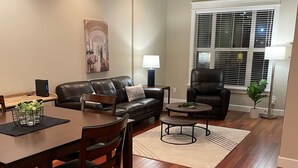 Un salon comprenant un coin repas, avec un canapé en cuir, une table basse et une table à manger avec des chaises.