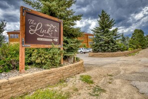 A sign for The Links condominiums at 109 Ace Court with a view of the surrounding area including trees and parked cars.