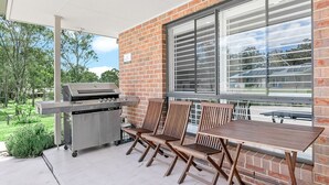 Eine Terrasse im Freien mit Grill, Holzstühlen und einem Tisch.