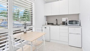 Een moderne keuken met witte kasten, een ingebouwde magnetron en een wijnfles op het aanrecht.