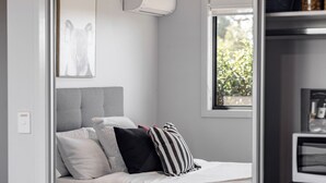 Een knus slaapkamer met een bed, nachtkastje en een raam.