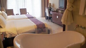 A hotel room with two beds, a bathtub, a desk with a lamp, and a robe hanging on the wall. - Huitang Zilongwan Hot Spring Holiday Hotel (Changsha)