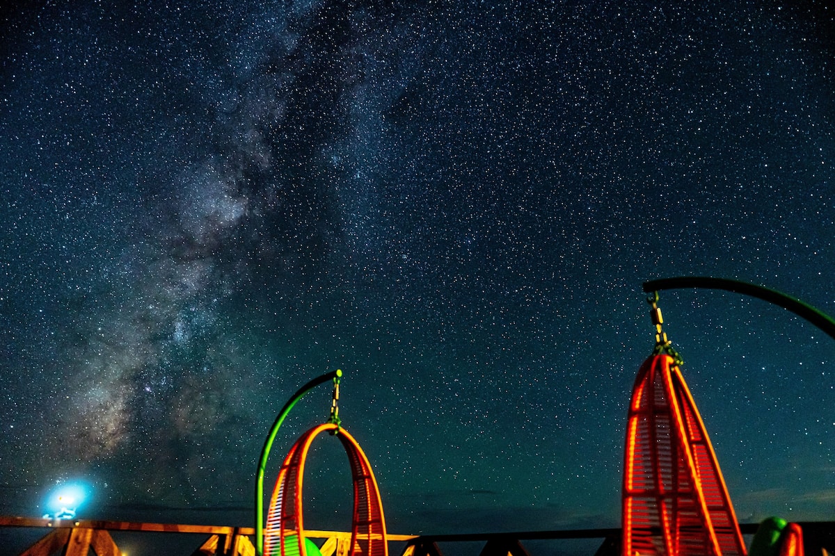 A night scene with a starry sky, a Ferris wheel, and a swing chair.