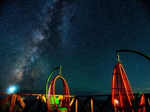 Una escena nocturna con cielo estrellado, noria y sillón colgante.